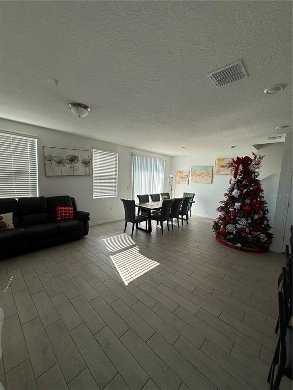 A living and dining room area features wood-look tile flooring and a decorated Christmas tree — 2130 CRAPE JASMINE LANE, ORLANDO, FL