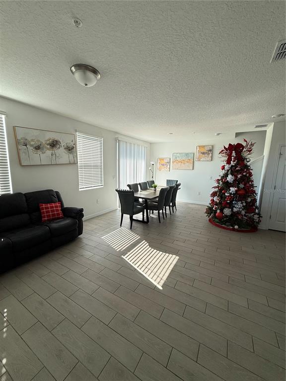 A living and dining area features light wood-look tile flooring, a black sofa, and a Christmas tree — 2130 CRAPE JASMINE LANE, ORLANDO, FL