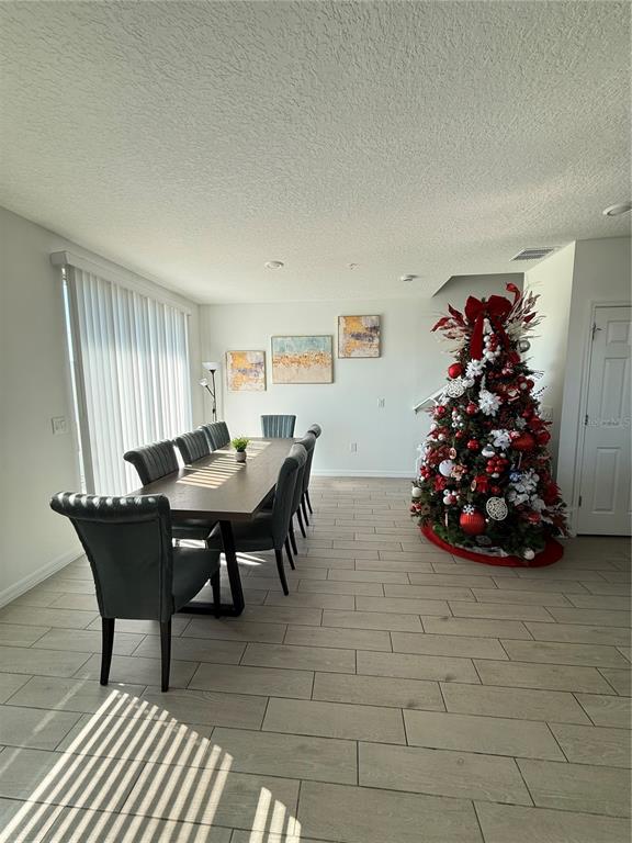 A dining room features a long wooden table, gray upholstered chairs, and a decorated Christmas tree — 2130 CRAPE JASMINE LANE, ORLANDO, FL