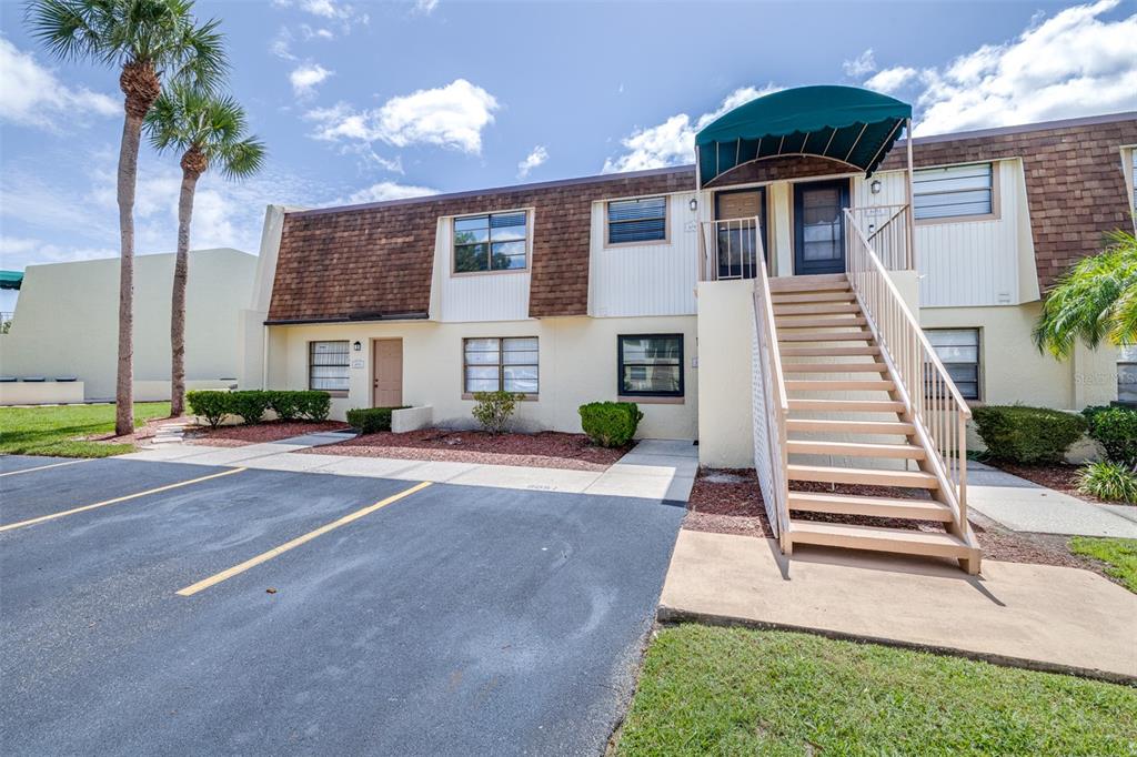 A two-story apartment building exterior features a central staircase leading to an upper-level entrance — 6045 TOPHER TRAIL UNIT C-24, MULBERRY, FL