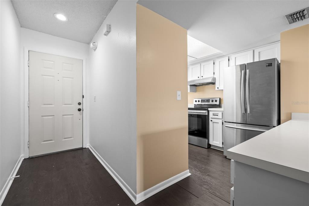 A view of an entryway leading into a kitchen with white cabinets and stainless appliances — 6045 TOPHER TRAIL UNIT C-24, MULBERRY, FL