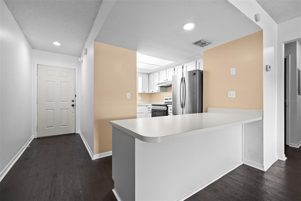 A kitchen with white cabinets and stainless steel appliances overlooks a breakfast bar and entryway — 6045 TOPHER TRAIL UNIT C-24, MULBERRY, FL