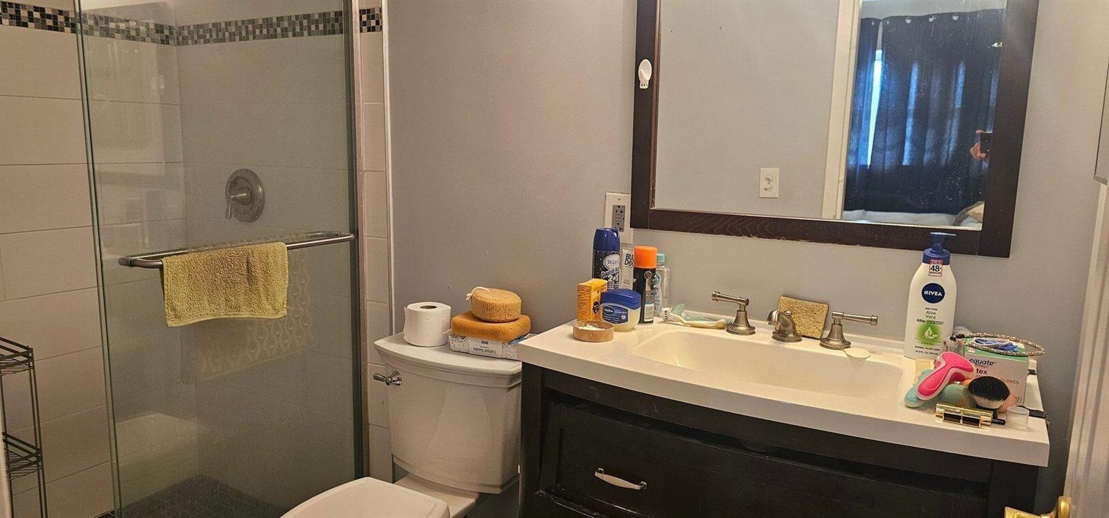 A bathroom features a glass-enclosed shower, a white vanity with a sink, and a toilet — 14721 Bonaire Boulevard # 309, Delray Beach FL 33446, DELRAY BEACH, FL