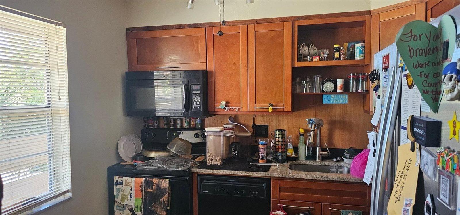 A kitchen with wood cabinets, a black microwave, a black dishwasher, and a stainless sink — 14721 Bonaire Boulevard # 309, Delray Beach FL 33446, DELRAY BEACH, FL