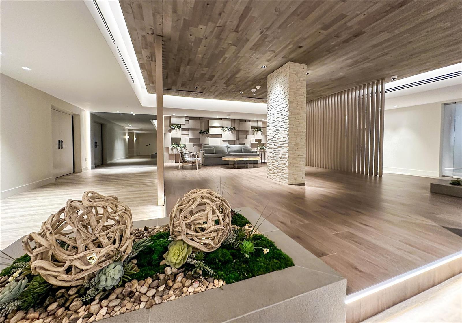 A modern lobby features wood-paneled ceilings, a stone pillar, and a decorative planter in foreground — 2301 Collins Avenue # 1015, Miami Beach FL 33139, MIAMI BEACH, FL