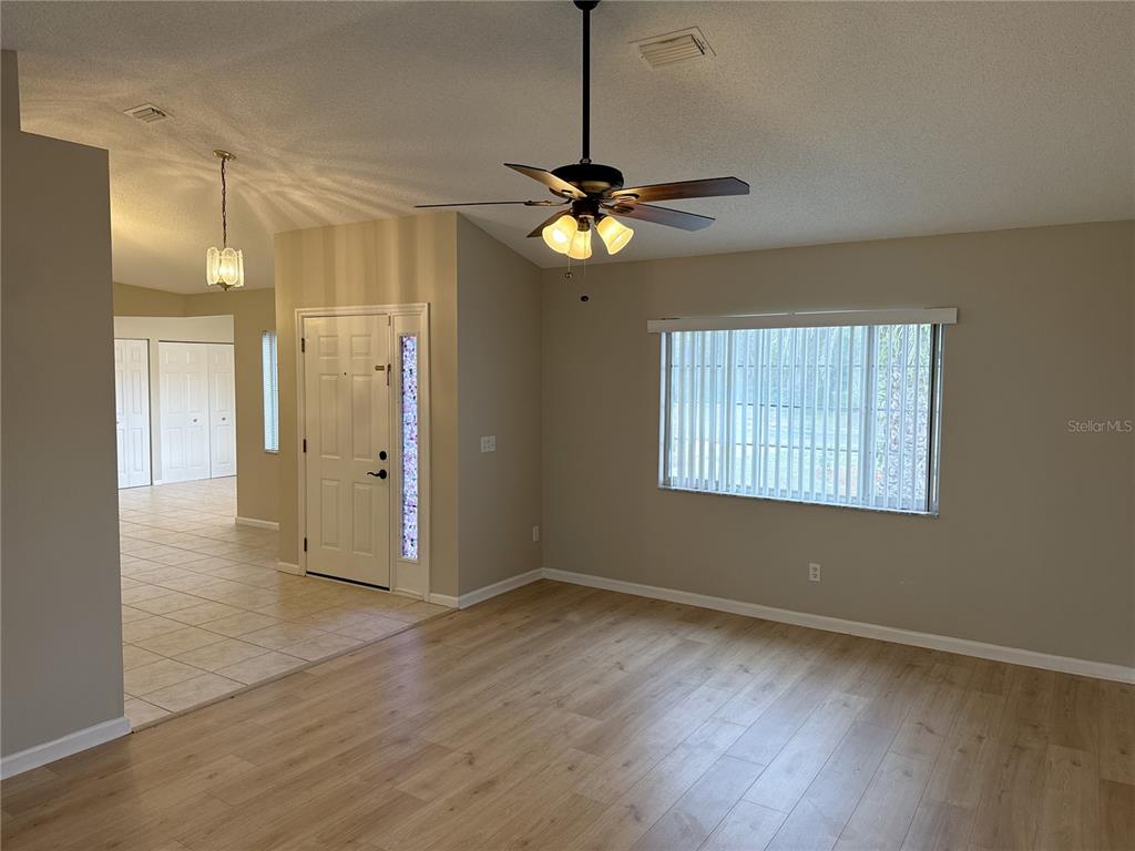 A living room with light wood-look flooring, a ceiling fan, and a front entry door — 1988 NW 50TH AVENUE, OCALA, FL