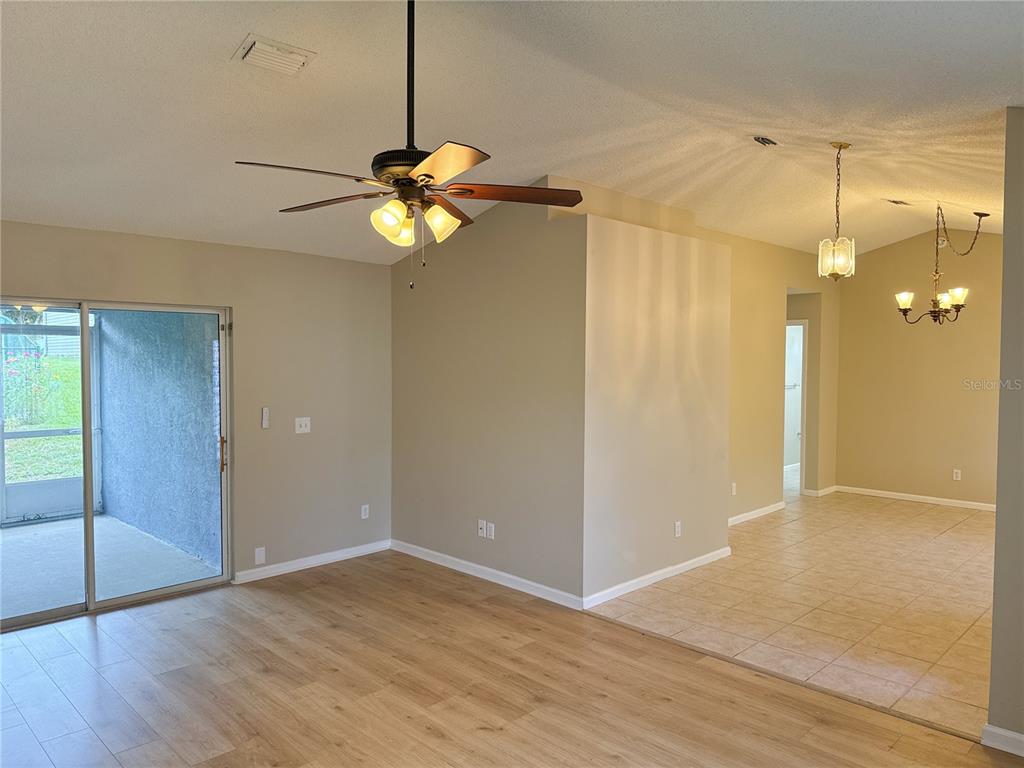 A living area with wood-look flooring, a ceiling fan, and an adjacent tiled dining space — 1988 NW 50TH AVENUE, OCALA, FL