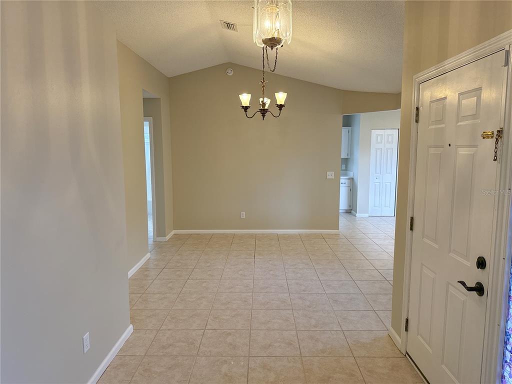 A tiled dining area features a vaulted ceiling, a chandelier, and an adjacent entryway — 1988 NW 50TH AVENUE, OCALA, FL