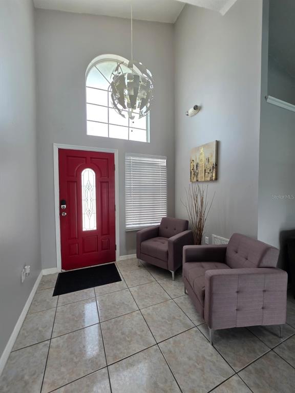 A bright entryway features a red front door, tiled floors, and two purple armchairs — 763 COUNTRY WOODS CIRCLE, KISSIMMEE, FL