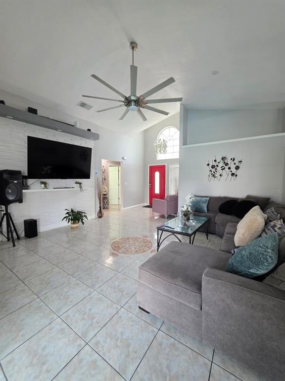 A living room features a white brick fireplace, tile flooring, and a large sectional sofa — 763 COUNTRY WOODS CIRCLE, KISSIMMEE, FL