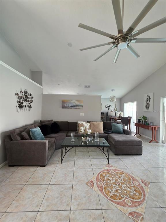 A living room features a large sectional sofa, a glass coffee table, and tile flooring — 763 COUNTRY WOODS CIRCLE, KISSIMMEE, FL