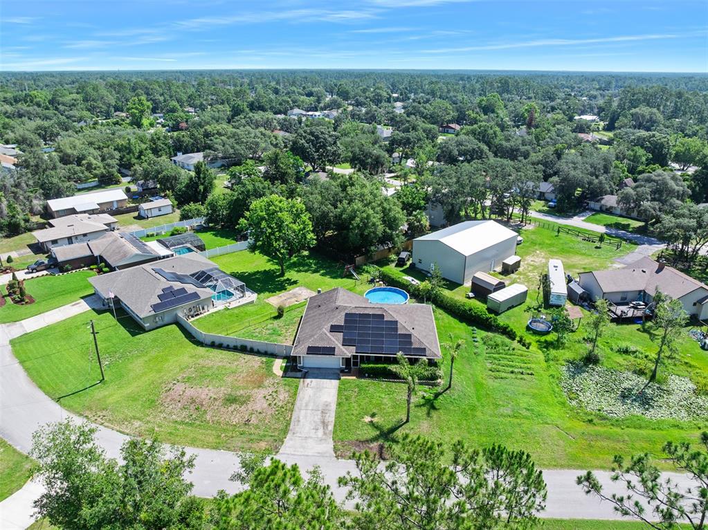 An aerial view shows a residential property with a solar-paneled house, pool, and detached garage — 1355 1ST AVENUE, DELAND, FL