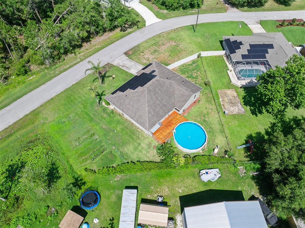 An aerial view shows a house with a wooden deck, above-ground pool, and solar panels — 1355 1ST AVENUE, DELAND, FL