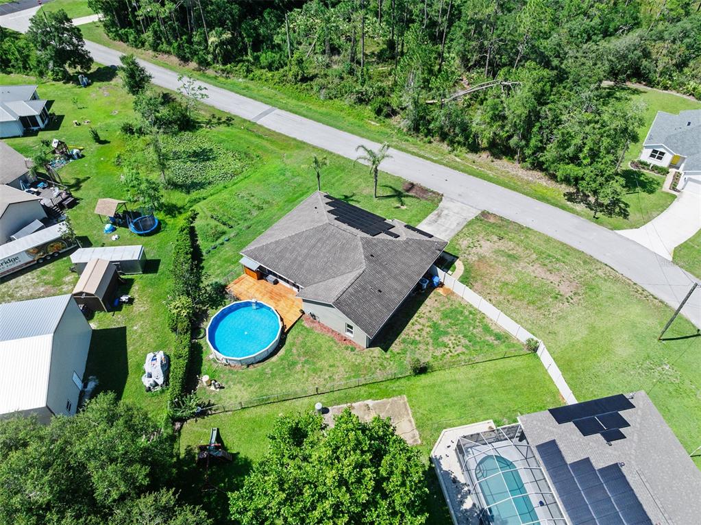 An aerial view shows a house with a backyard pool, deck, and solar panels — 1355 1ST AVENUE, DELAND, FL