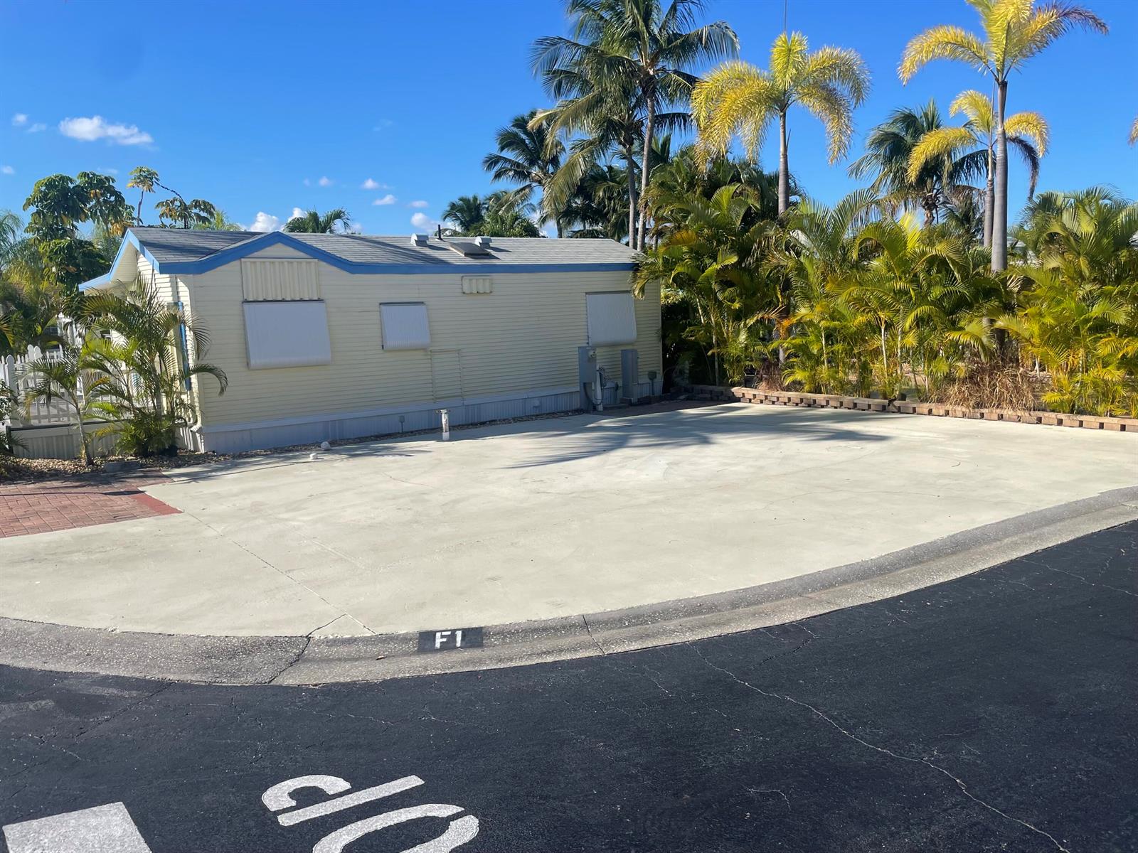 A light-colored mobile home sits next to a large concrete parking pad labeled F1 — 900 Juno Ocean Walk F1, Juno Beach FL 33408, JUNO BEACH, FL