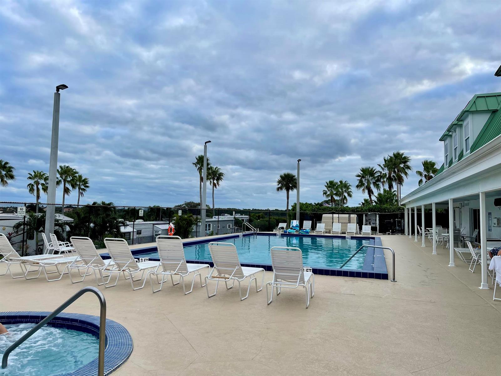 An outdoor swimming pool and hot tub are surrounded by lounge chairs and palm trees — 900 Juno Ocean Walk F1, Juno Beach FL 33408, JUNO BEACH, FL