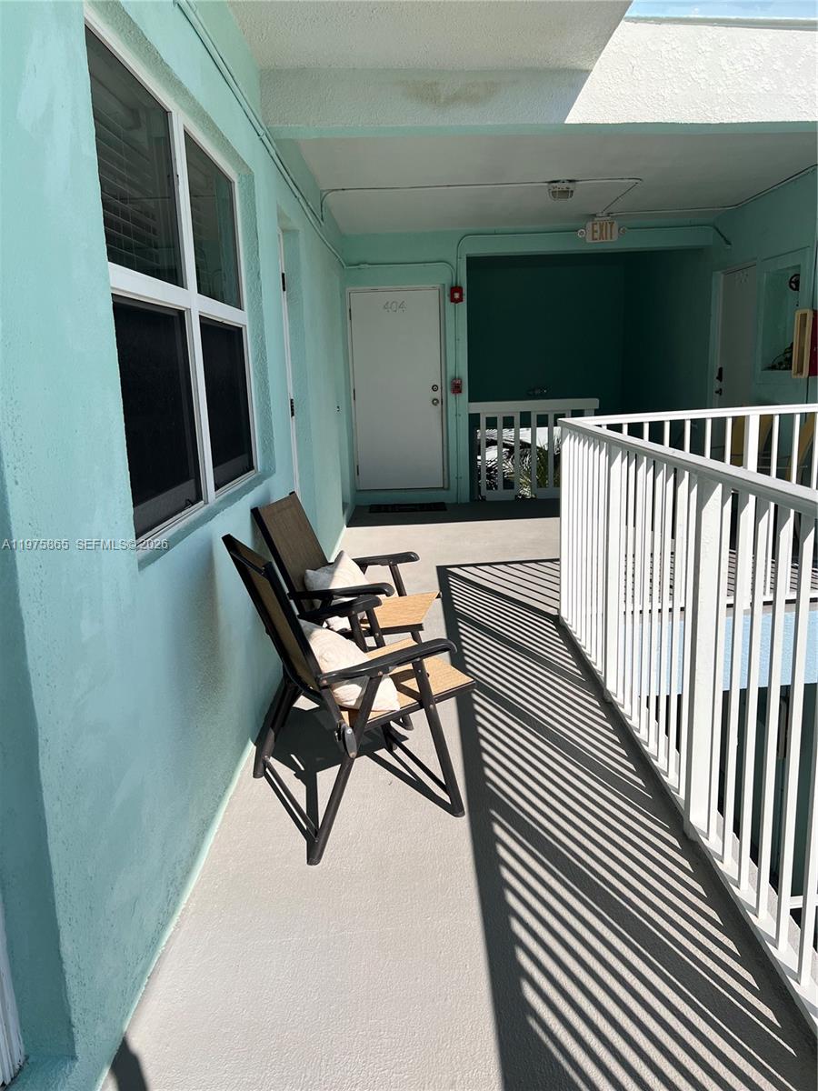 An outdoor walkway features a light blue wall, two folding chairs, and a white railing — 2600 N Surf Rd # 403, Hollywood FL 33019, HOLLYWOOD, FL