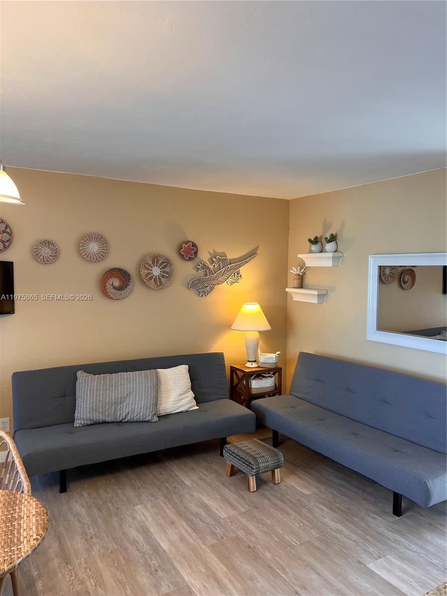 A living room features two gray futons, a small side table, and wall-mounted woven decor — 2600 N Surf Rd # 403, Hollywood FL 33019, HOLLYWOOD, FL