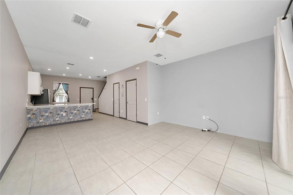 An open-concept living area features light tile flooring, a ceiling fan, and a kitchen island — 2060 VIEWFINDER STREET, KISSIMMEE, FL