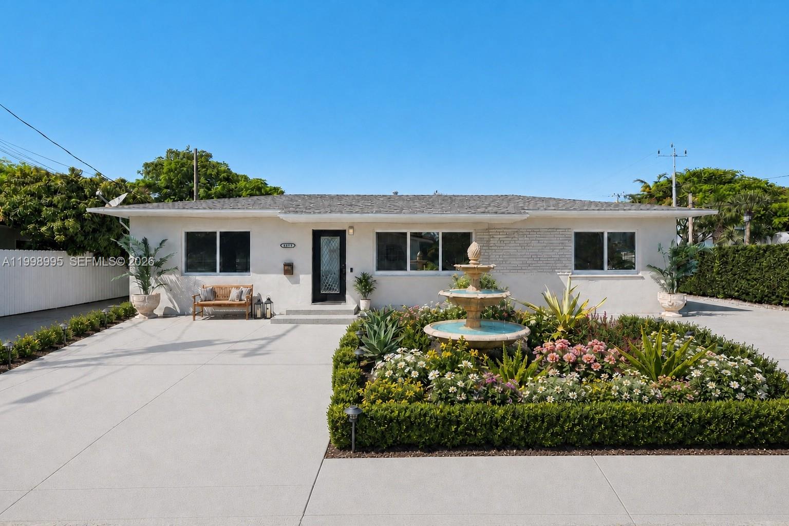 A single-story white house features a front fountain, a landscaped garden, and a concrete driveway — 1682 NE 124th Ln, North Miami FL 33181, NORTH MIAMI, FL