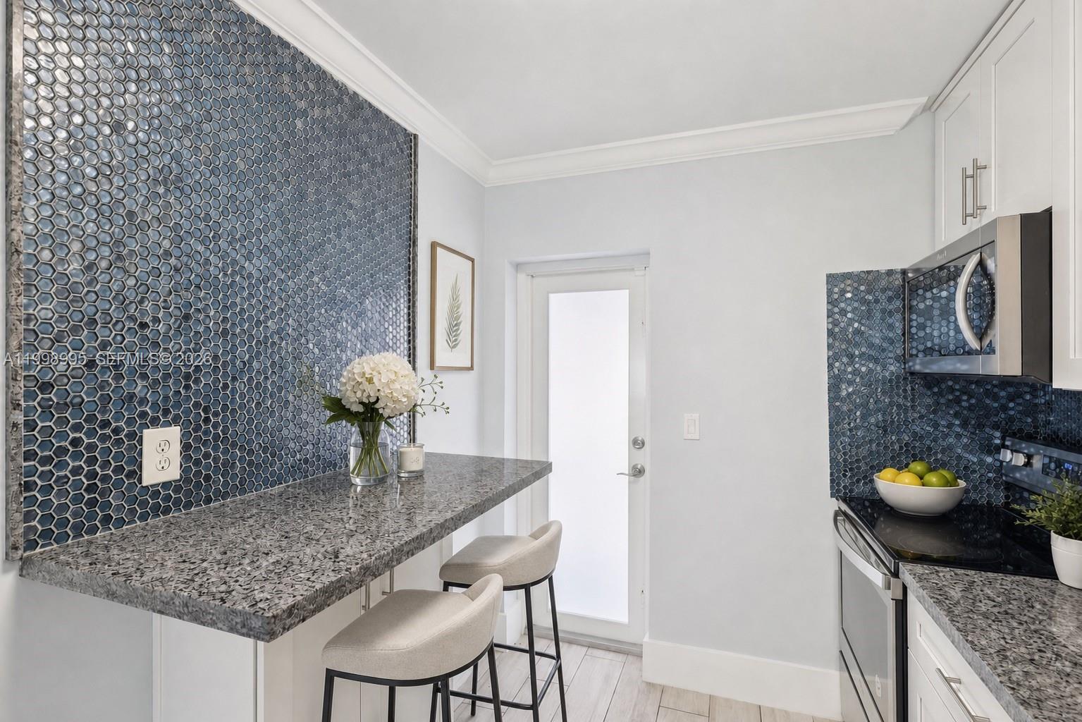 A kitchen features a blue hexagonal tile backsplash, granite countertops, and a breakfast bar — 1682 NE 124th Ln, North Miami FL 33181, NORTH MIAMI, FL