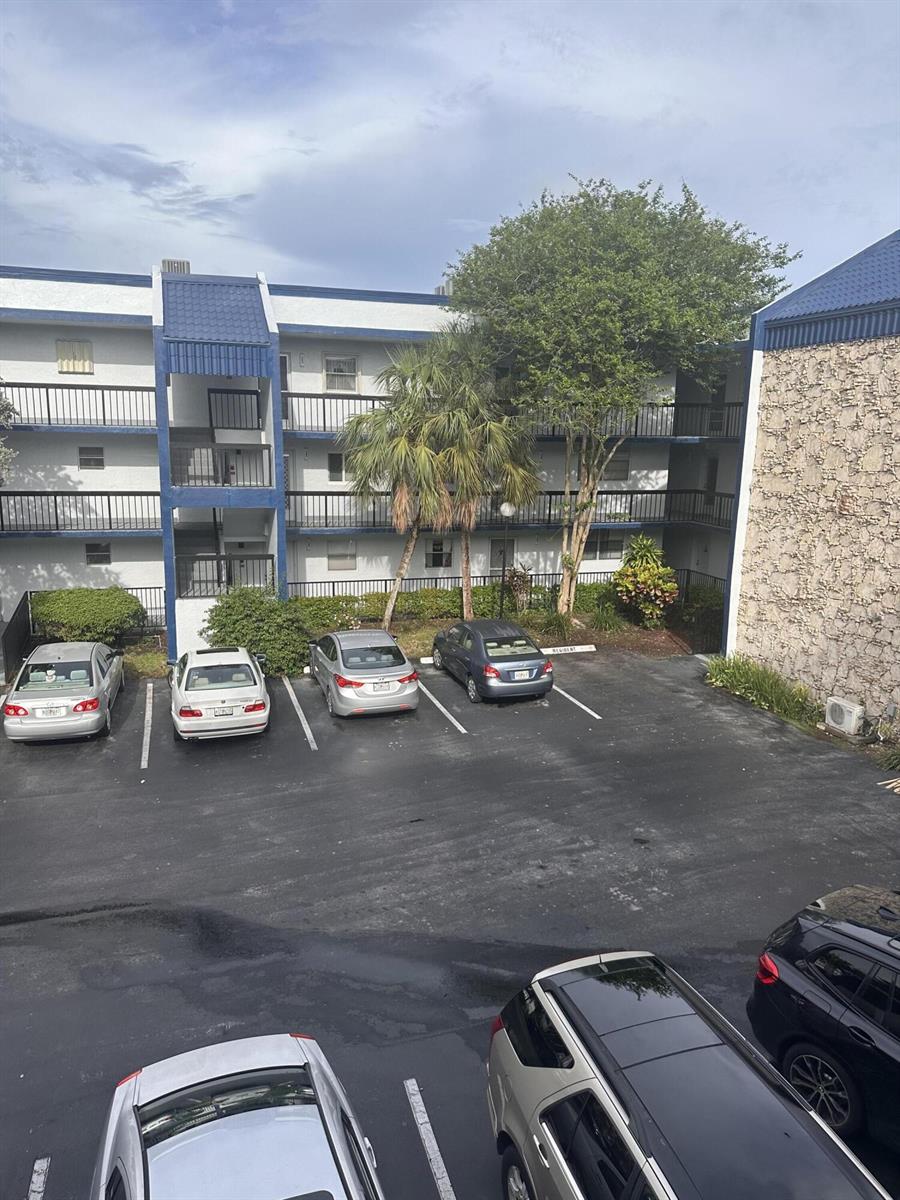 An exterior view of a multi-story apartment building with a parking lot in front — 3090 Holiday Springs Boulevard # 310, Margate FL 33063, MARGATE, FL