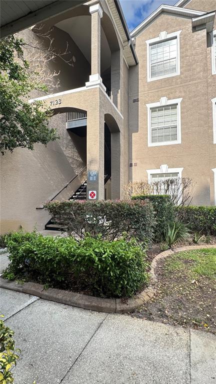 An exterior view of a multi-story apartment building with a staircase and landscaped bushes — 7123 YACHT BASIN AVENUE UNIT 312, ORLANDO, FL