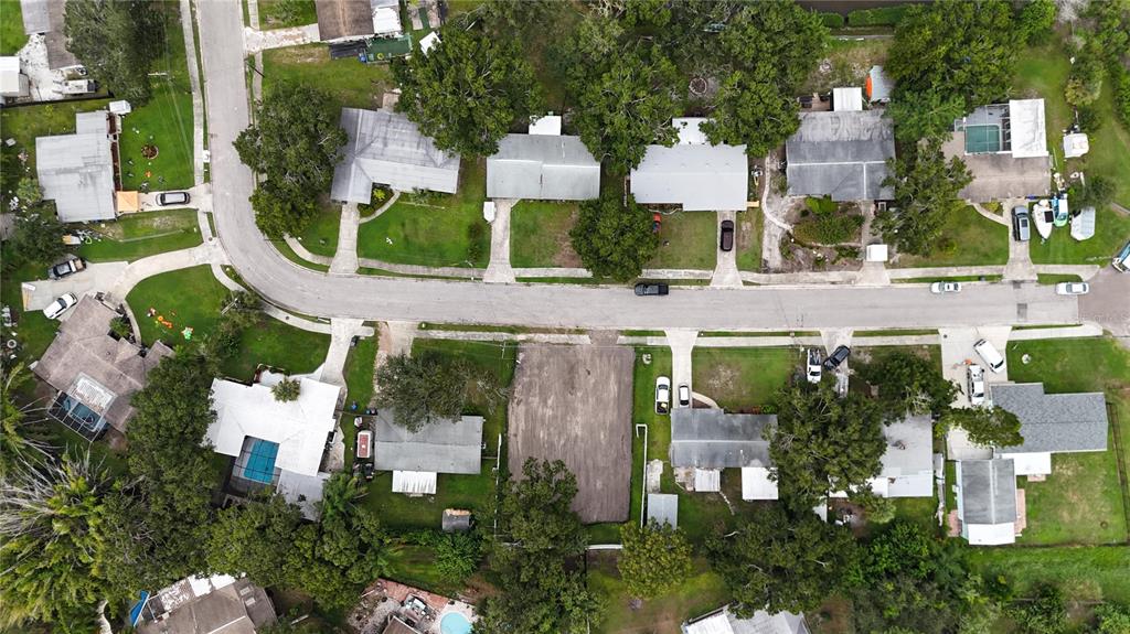 This aerial view shows a suburban neighborhood street with houses, driveways, and a vacant lot — 436 COUNTRY CLUB DRIVE, OLDSMAR, FL