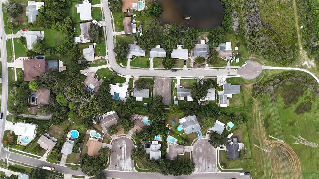 This aerial view shows a residential neighborhood with houses, swimming pools, and a small lake — 436 COUNTRY CLUB DRIVE, OLDSMAR, FL