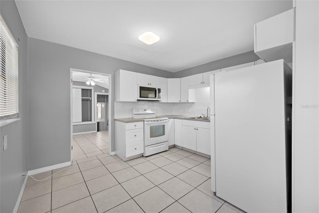 A kitchen with white cabinets, white appliances, and light-colored tile flooring — 3246 20TH AVENUE S, ST PETERSBURG, FL