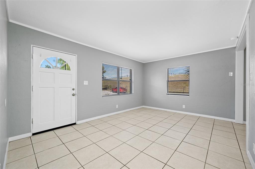 An empty room with gray walls, light-colored tile flooring, two windows, and a white door — 3246 20TH AVENUE S, ST PETERSBURG, FL