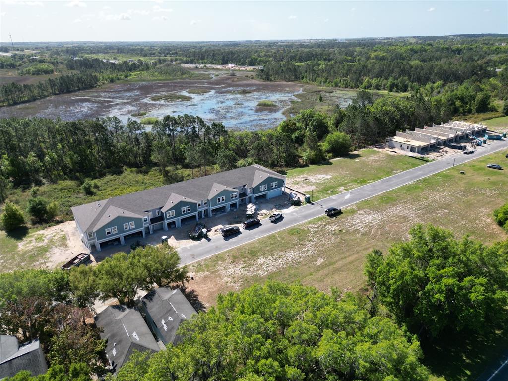 An aerial view shows a new townhouse construction project near a large wetland area — 214 GLASS ONION DRIVE, HOWEY IN THE HILLS, FL