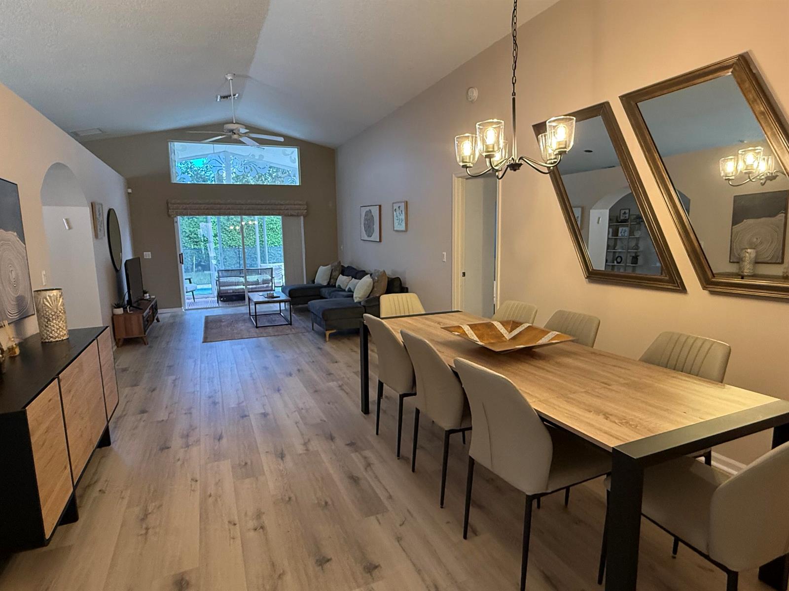 An open-concept dining and living area features wood-look flooring, vaulted ceilings, and a sliding door — 5730 Royal Club Drive, Boynton Beach FL 33437, BOYNTON BEACH, FL
