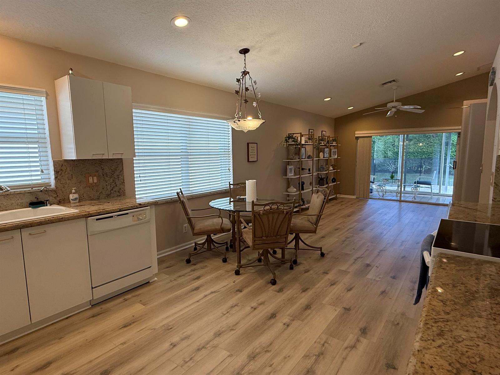 A kitchen and dining area with light wood flooring, white cabinets, and a glass table — 5730 Royal Club Drive, Boynton Beach FL 33437, BOYNTON BEACH, FL