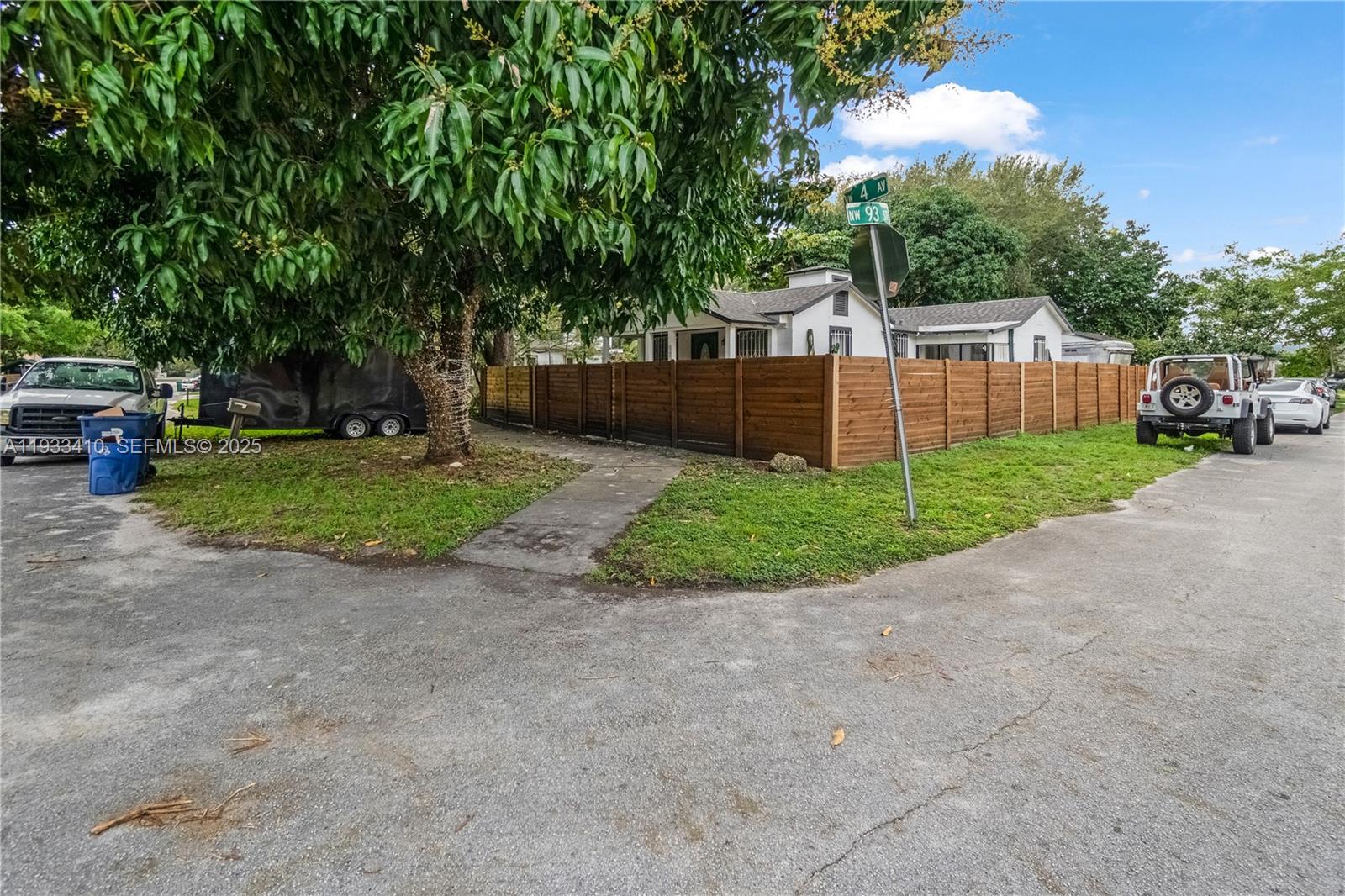 A corner lot features a house enclosed by a wooden fence with a large tree — 9210 NW 4th Ave, Miami FL 33150, MIAMI, FL