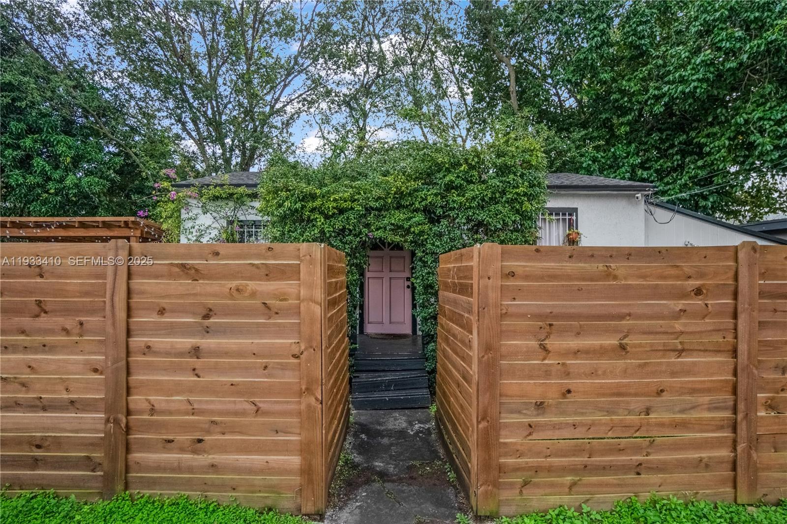 A wooden fence frames a path leading to a house entrance with a pink door — 9210 NW 4th Ave, Miami FL 33150, MIAMI, FL