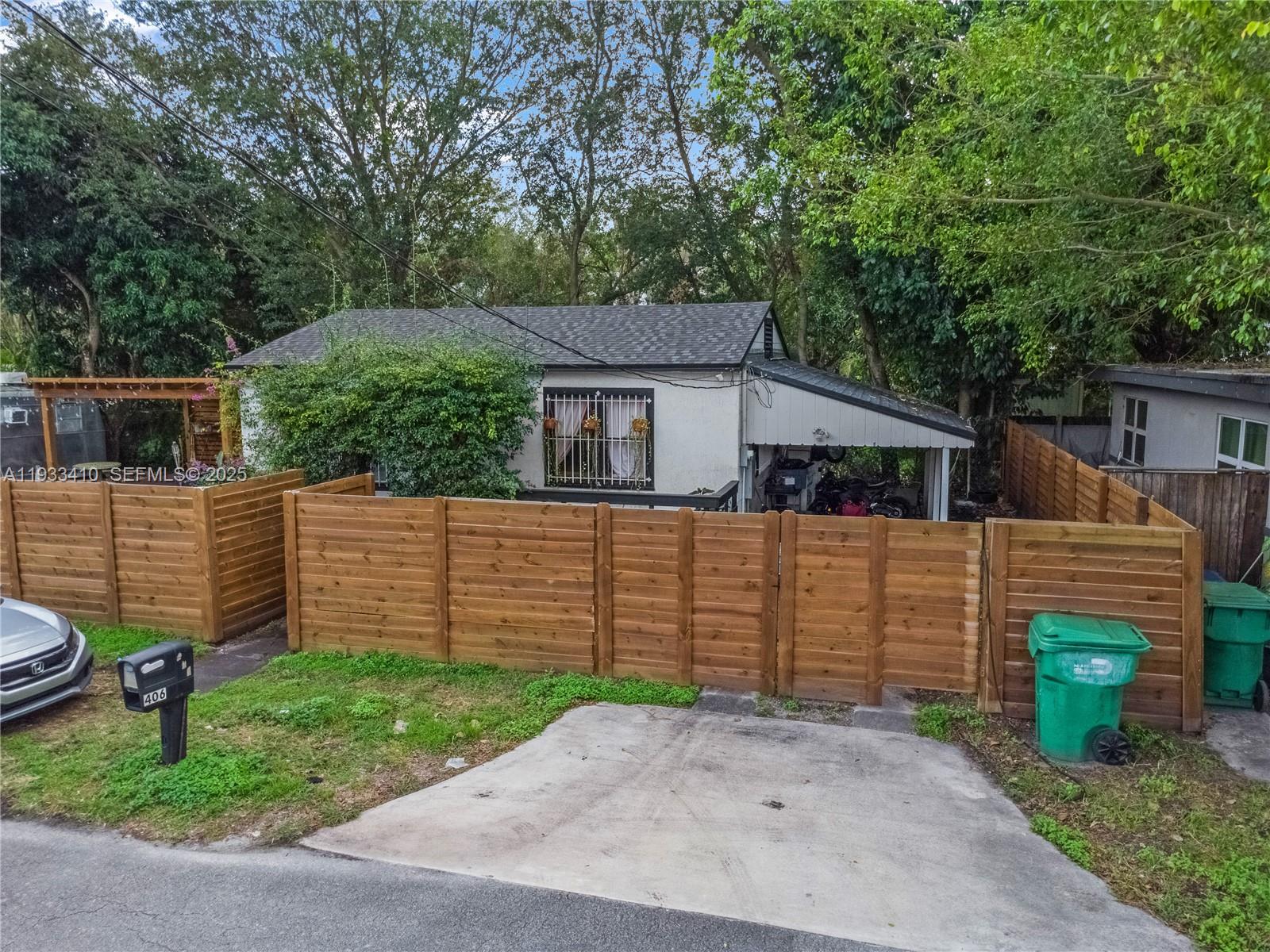 A single-story house with a carport is enclosed by a wooden fence — 9210 NW 4th Ave, Miami FL 33150, MIAMI, FL