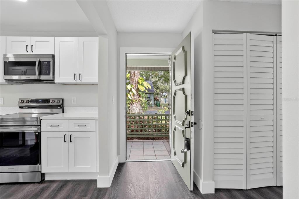 A kitchen with white cabinets and stainless steel appliances opens to an outdoor patio area — 5014 BARRINGTON CIRCLE UNIT 2102, SARASOTA, FL