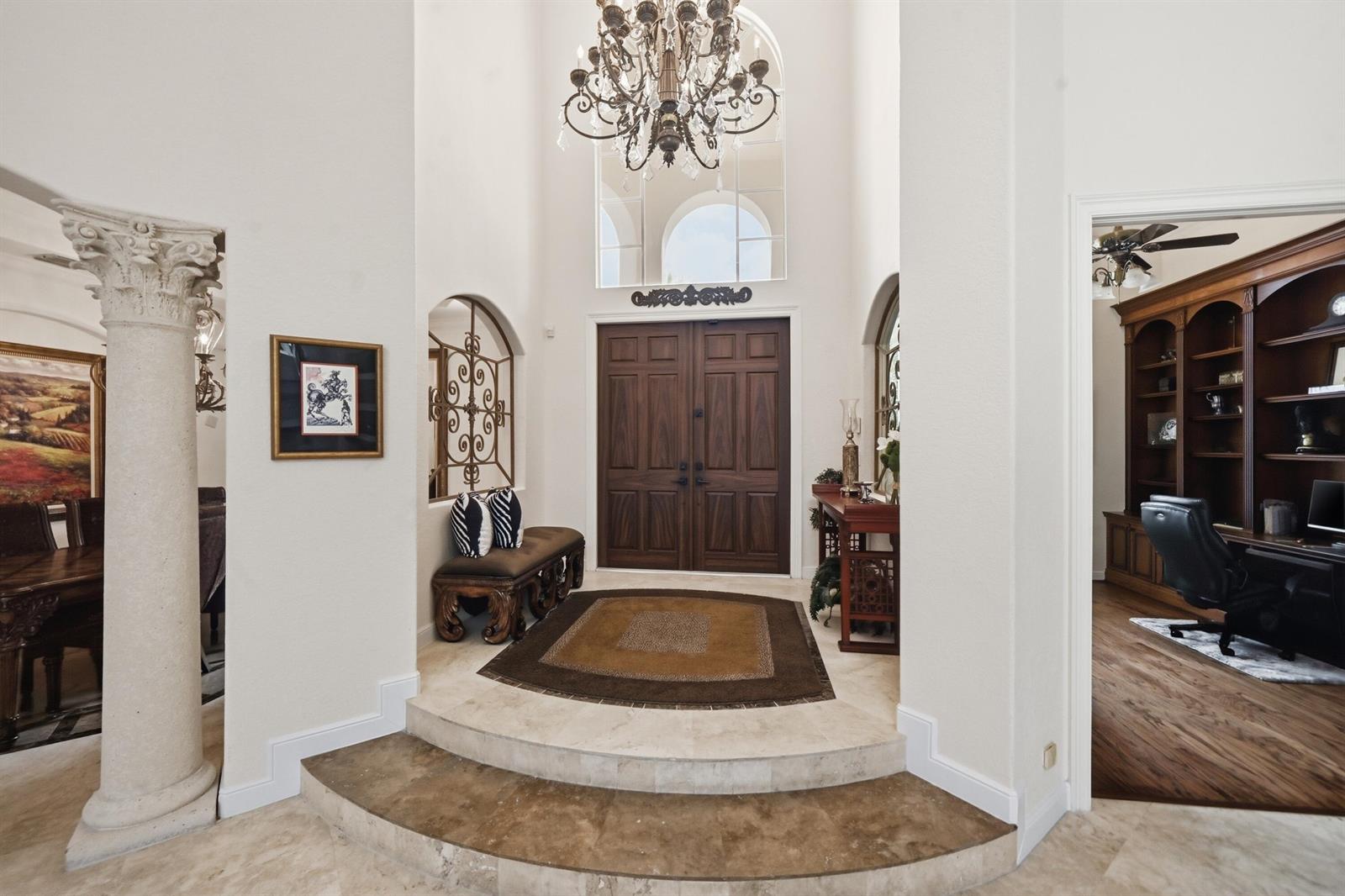 A grand foyer features a double-door entrance, a chandelier, and a raised stone landing — 2425 NW 49th Lane, Boca Raton FL 33431, BOCA RATON, FL