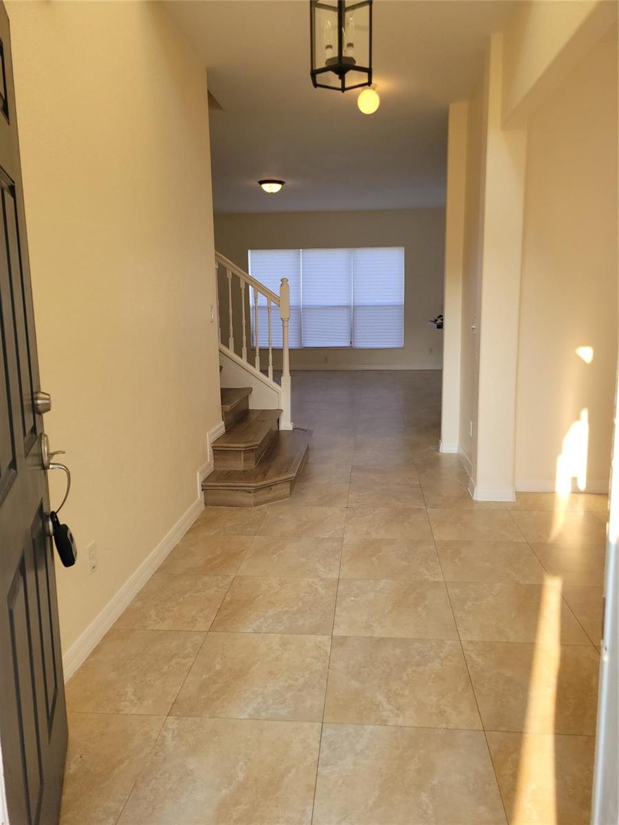 An entryway features tan tile flooring, a staircase with wood steps, and a hanging light fixture — 8448 Adele Road, Lakeland FL 33810, LAKELAND, FL
