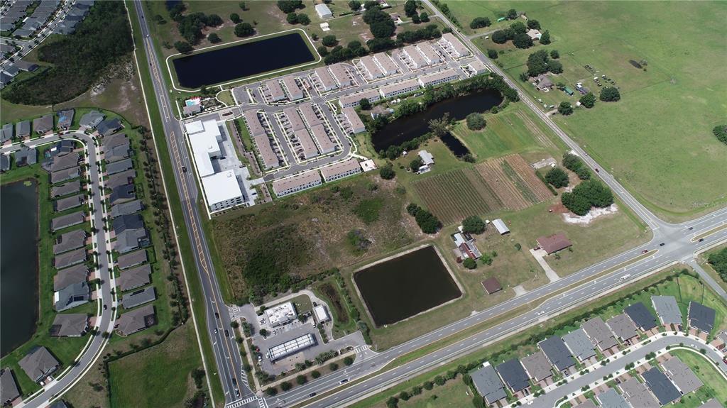 An aerial view shows a suburban neighborhood with residential townhomes, ponds, and undeveloped land — HICKORY TREE ROAD, ST CLOUD, FL