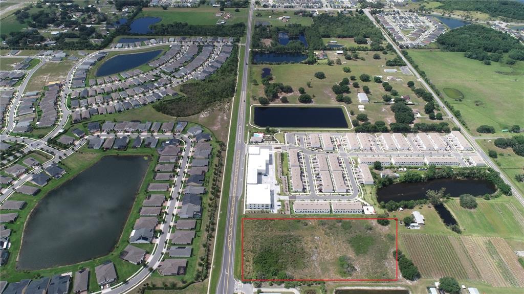 An aerial view shows a vacant rectangular plot of land outlined in red near housing — HICKORY TREE ROAD, ST CLOUD, FL