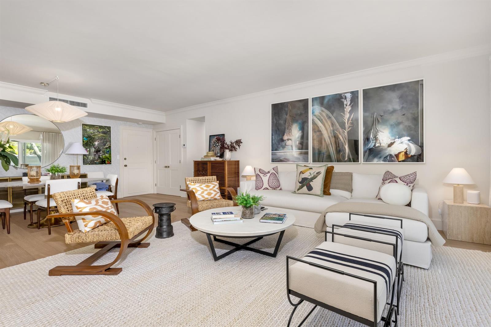 A bright living room features a white sectional, round coffee table, and three large wall artworks — 250 Bradley Place # 307, Palm Beach FL 33480, PALM BEACH, FL