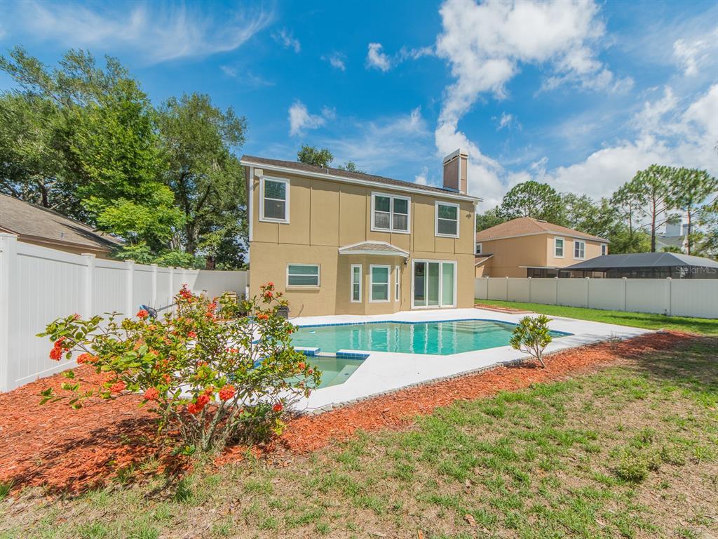 A two-story tan house with a backyard swimming pool and white vinyl fencing — 3256 BENTLEY DRIVE, PALM HARBOR, FL