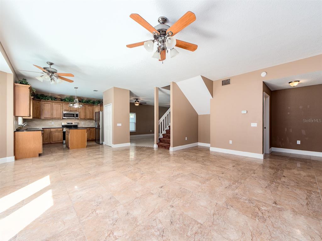 An open-concept living area features tile flooring, a kitchen with wood cabinets, and a staircase — 3256 BENTLEY DRIVE, PALM HARBOR, FL