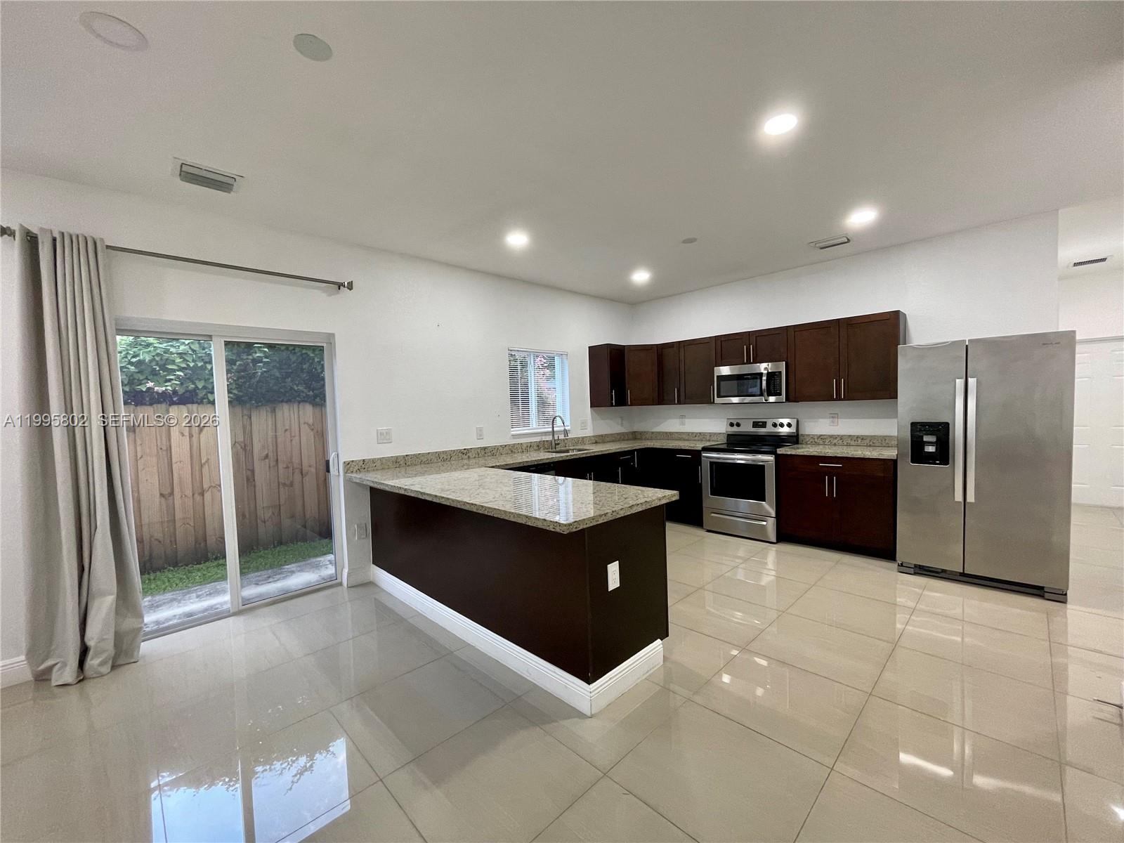 A kitchen features dark wood cabinets, granite countertops, stainless steel appliances, and light tile flooring — 1531 NW 55th Ter # 1533, Miami FL 33142, MIAMI, FL