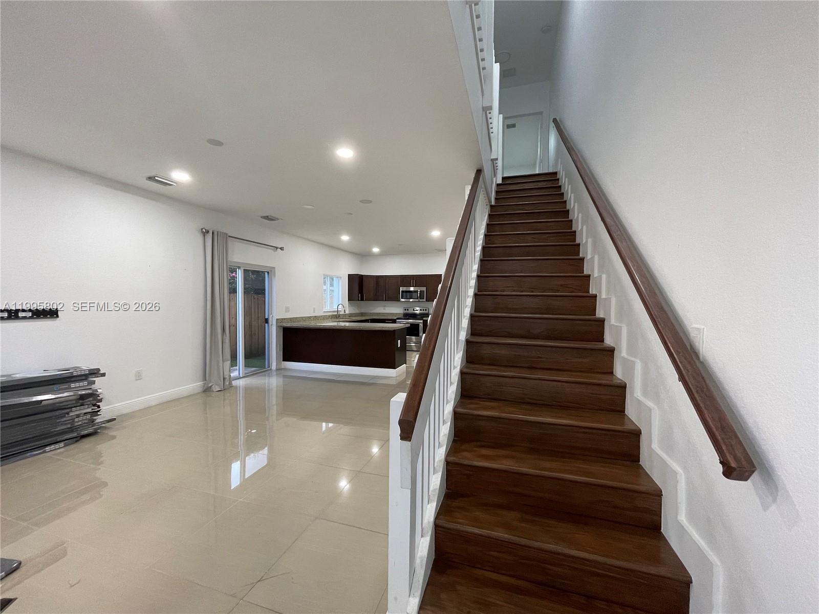 An open-concept living area features tile flooring, a kitchen with dark cabinetry, and wooden stairs — 1531 NW 55th Ter # 1533, Miami FL 33142, MIAMI, FL