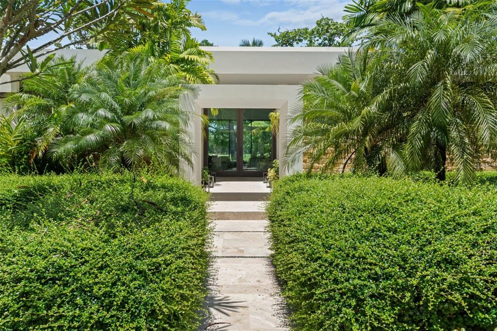 A stone walkway leads through manicured hedges to the glass-fronted entrance of a modern home — 2200 DORADO BEACH DR UNIT 3, DORADO, PR