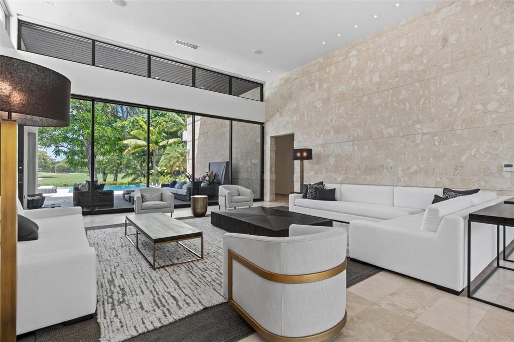 A modern living room features a large stone wall, white sofas, and floor-to-ceiling glass windows — 2200 DORADO BEACH DR UNIT 3, DORADO, PR