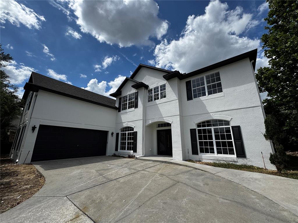 A two-story white stucco house with a dark garage door and black window shutters — 219 LARGOVISTA DRIVE, OAKLAND, FL